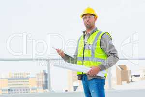 Architect holding blueprints and clipboard outdoors