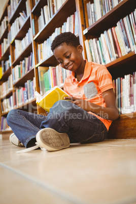 Cute boy reading book in library