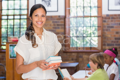 Pretty teacher smiling at camera in library