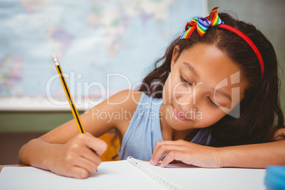 Little girl writing book in classroom