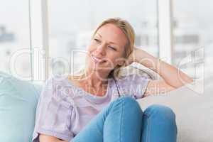 Relaxed woman looking away while sitting on sofa