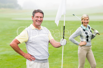 Happy golfer holding flag for cheering partner