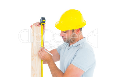 Carpenter using measure tape to mark on wooden plank