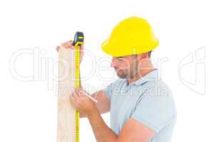 Carpenter using measure tape to mark on wooden plank
