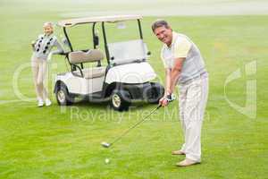 Golfer about to tee off with partner behind him