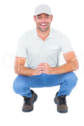 Cheerful handyman crouching on white background