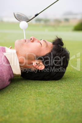 Golfer teeing off from lying man mouth