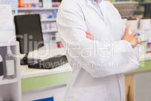 Mid section of junior pharmacist with arms crossed