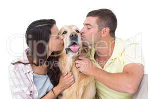 Couple with eyes closed kissing dog