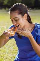 Pretty woman eating pizza in the park