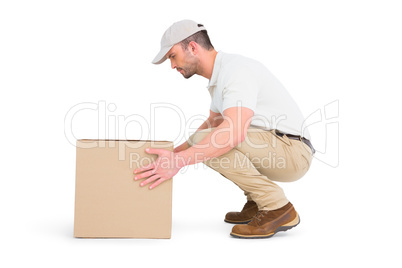 Delivery man crouching while picking cardboard box