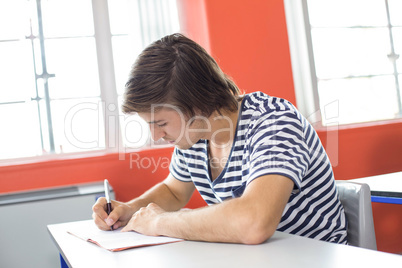 Male student writing notes in classroom