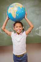 Cute little girl holding globe over head