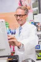 Smiling pharmacist using the computer