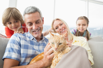 Family sitting with cat on sofa at home