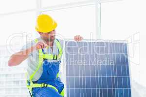 Worker tightening solar panel in office