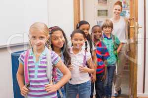 Cute pupils smiling at camera in classroom