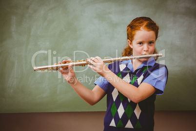 Cute little girl playing flute in classroom