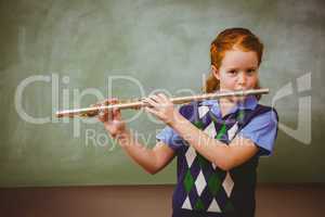 Cute little girl playing flute in classroom