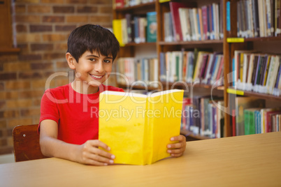 Portrait of boy reading book in library