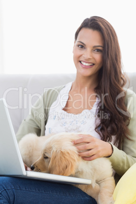 Happy woman with dog using laptop on sofa