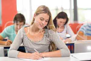 Female student writing notes in classroom