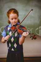 Cute little girl playing violin in classroom