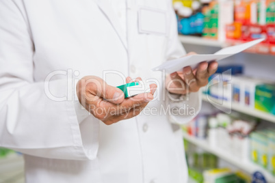 Pharmacist reading prescription and holding medicine