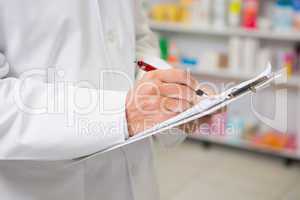 Close up of pharmacist writing on clipboard