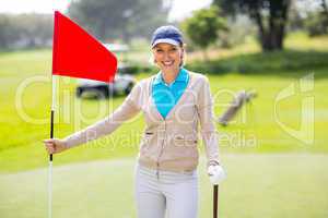 Female golfer smiling at camera and holding her golf club