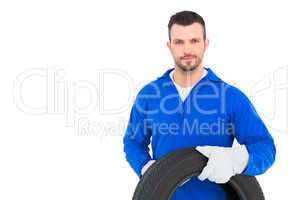 Smiling male mechanic holding tire