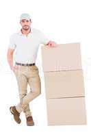 Confident delivery man leaning on cardboard boxes
