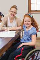 Pretty teacher helping pupil in classroom