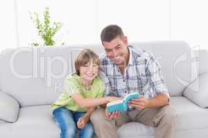 Father and son with story book sitting on sofa