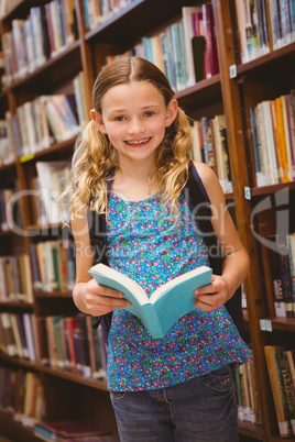 Cute little girl reading book in library