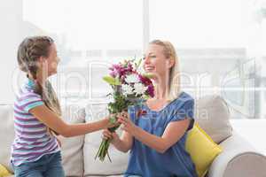 Girl giving bouquet to mother at home