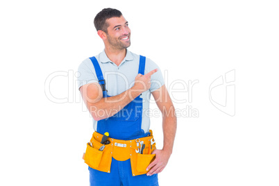 Repairman in overalls pointing on white background