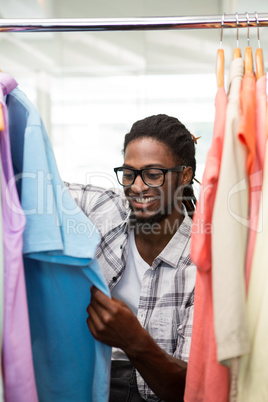 Male fashion designer looking at rack of clothes