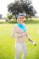 Female golfer standing holding her club smiling at camera