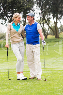 Golfing couple smiling at each other on the putting green