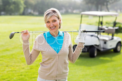 Cheerful golfer standing on the putting green