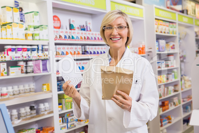 Smiling pharmacist holding prescription and envelope