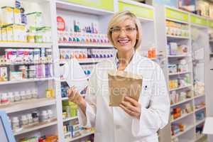 Smiling pharmacist holding prescription and envelope