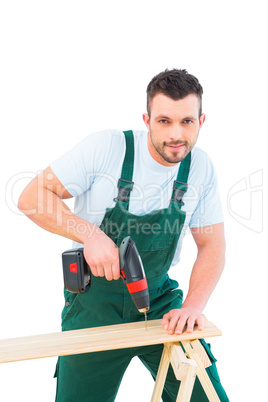 Carpenter drilling hole in plank