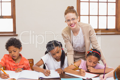 Cute pupils getting help from teacher in classroom