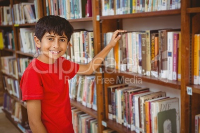 Portrait of boy selecting book in library
