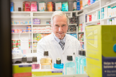 Smiling senior pharmacist standing behind a shelf Smiling senior pharmacist standing behind a shelf