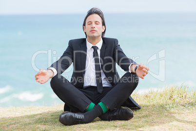 Peaceful businessman sitting in lotus pose relaxing