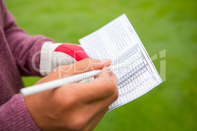 Golfer writing his points in paper