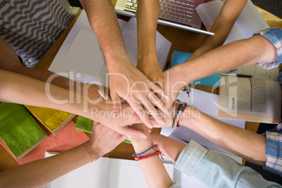 Students placing hands together over library table